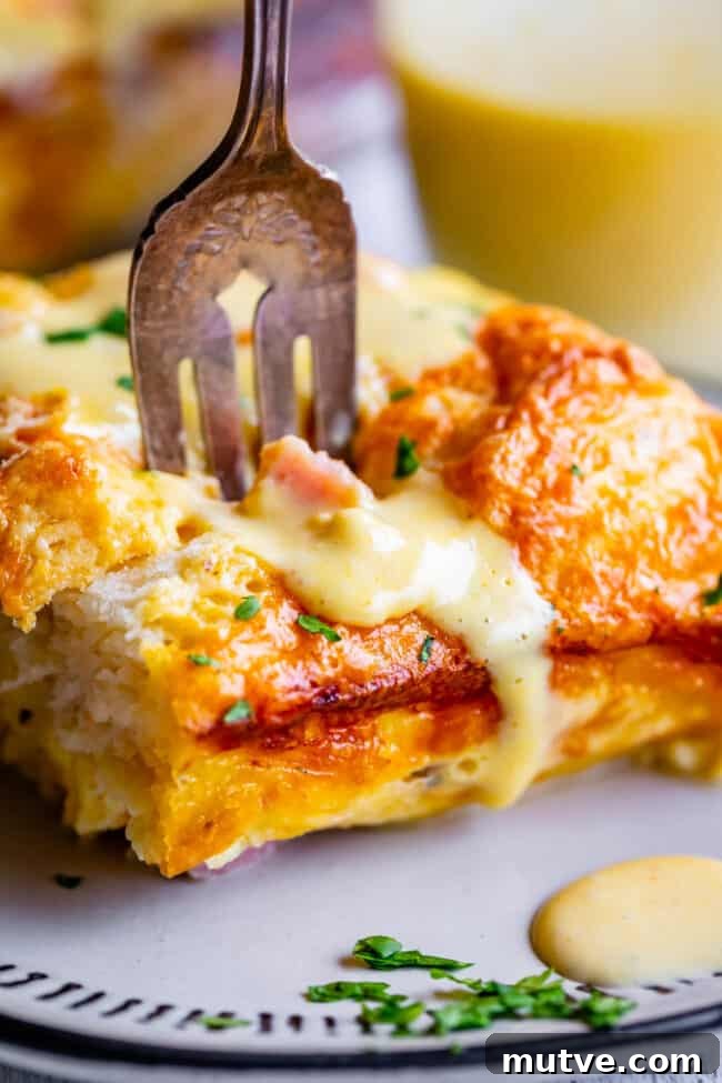 Cheesy Biscuit-Topped Breakfast Casserole Recipe 5 biscuit, ham, and egg breakfast casserole with a fork in the top and hollandaise melting off.