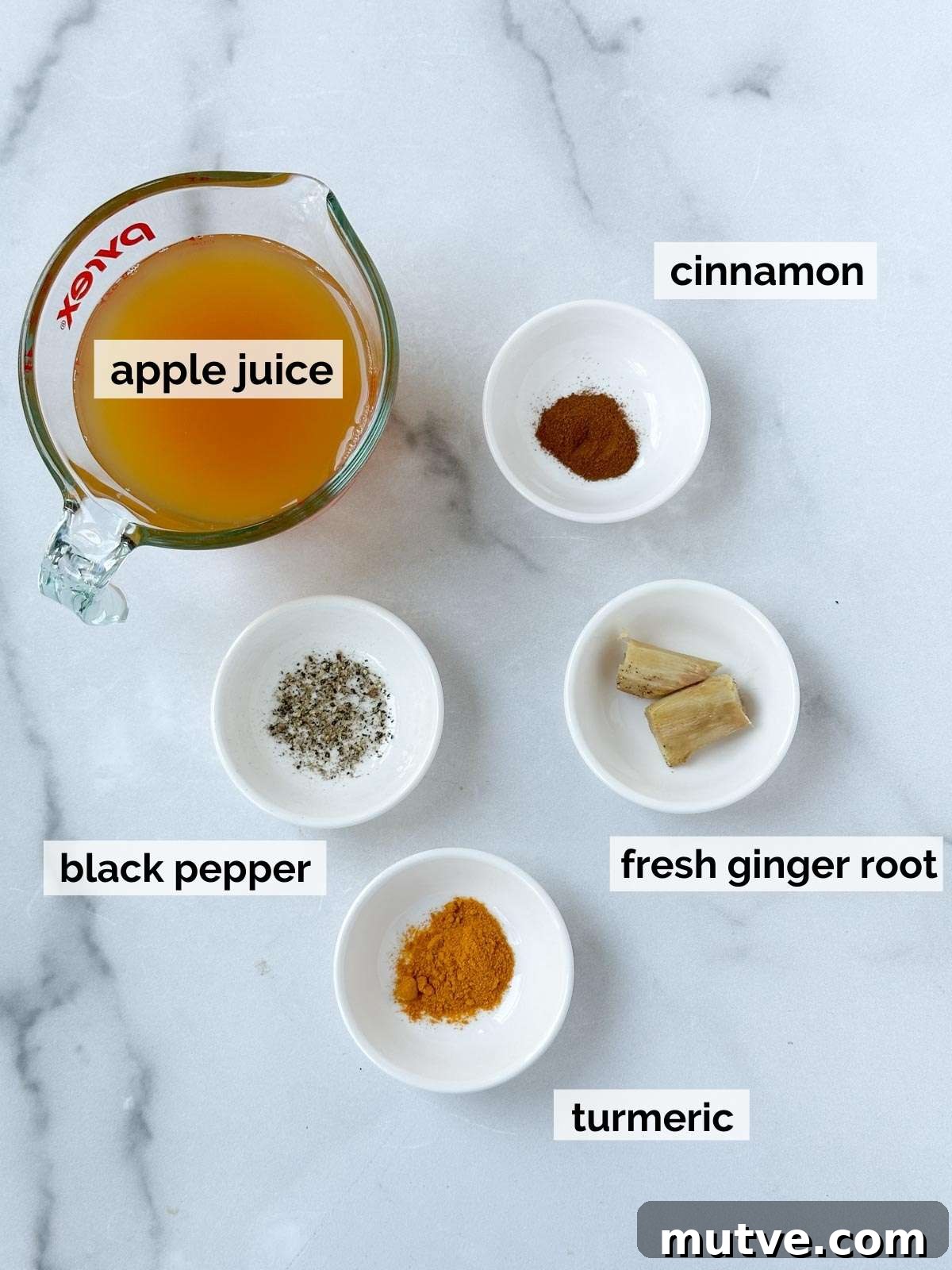 Ginger Turmeric Shots Recipe in a Blender 3 Apple juice, turmeric, ginger, pepper, and cinnamon on a white background.