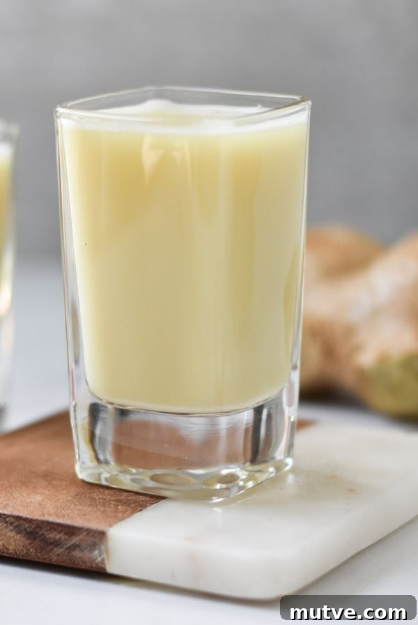 Two shots of ginger juice on a coaster.