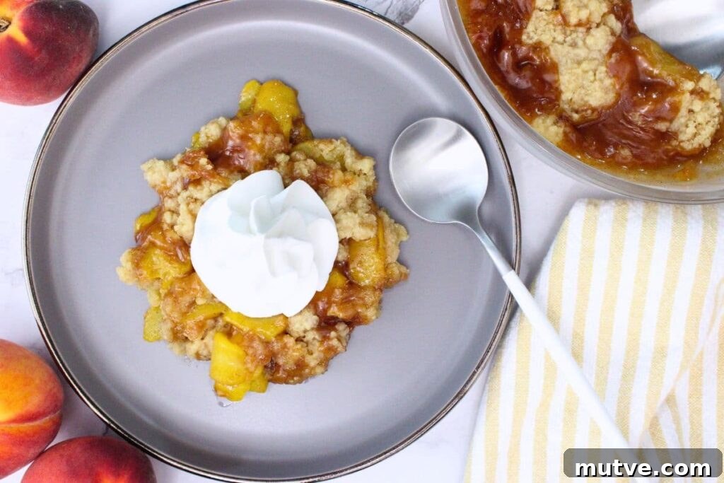 Quick Microwave Peach Crumble Recipe 8 overhead view of microwave peach crumble on a plate with a spoon and topped with whipped cream