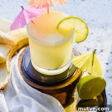 banana margarita with two drink umbrellas and lime garnish