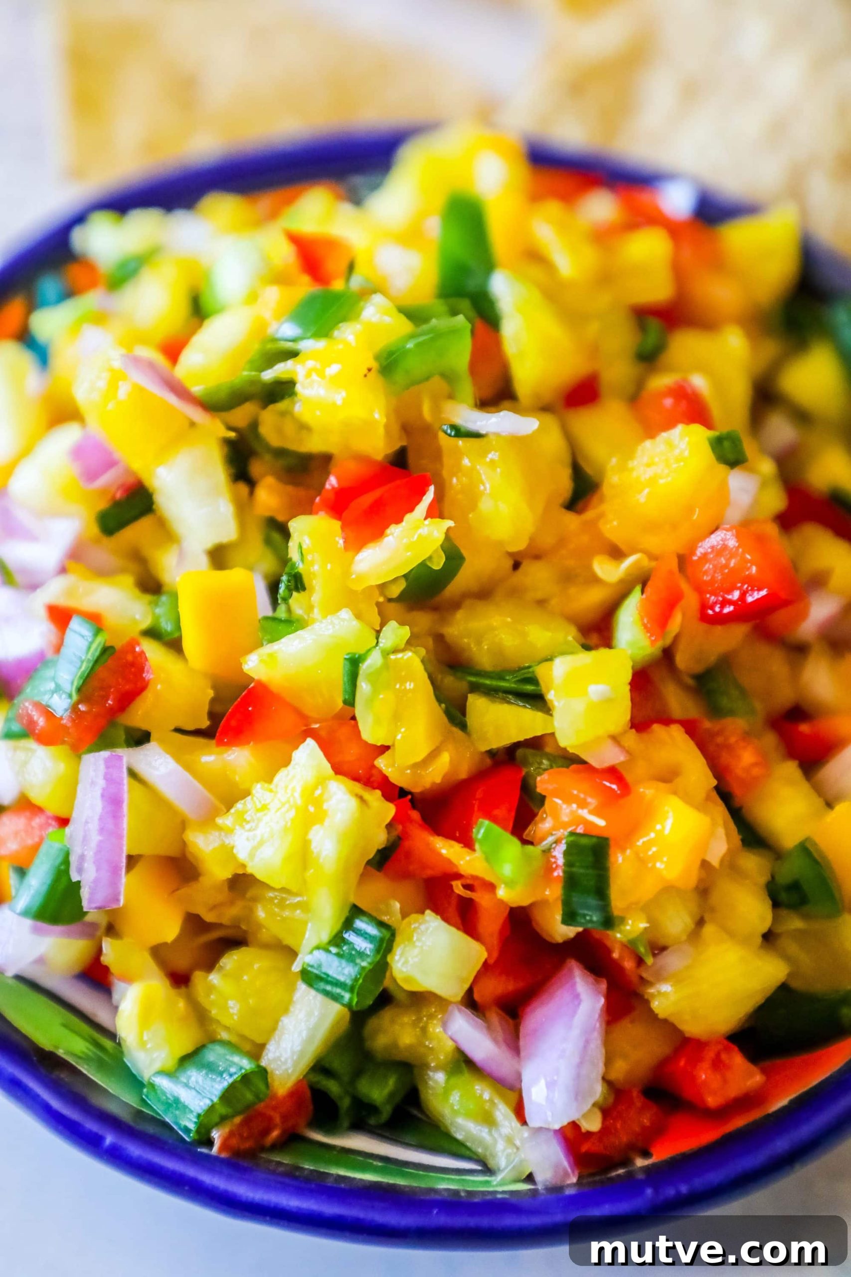 Spicy Pineapple Mango Salsa Recipe 2 bowl with pineapple, jalapeno, red onion, and green onions, chips behind it