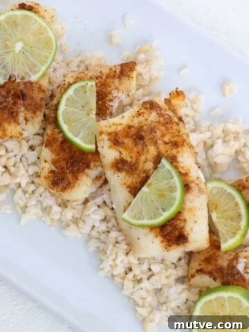 Air-fried cod topped with seasoning and slices of fresh lime on a white dish.