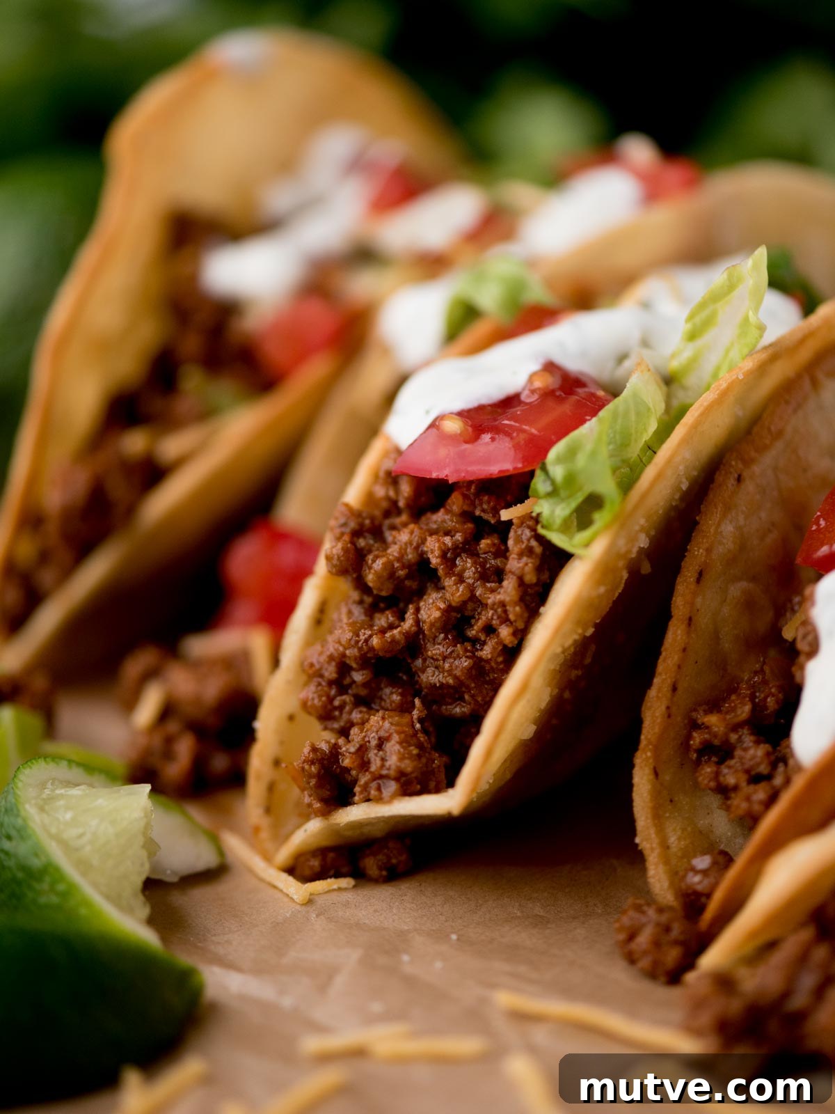 How to Make Ground Beef Tacos: Flavorful Step-by-Step Recipe 6 ground beef tacos on parchment paper surrounded by cilantro and limes