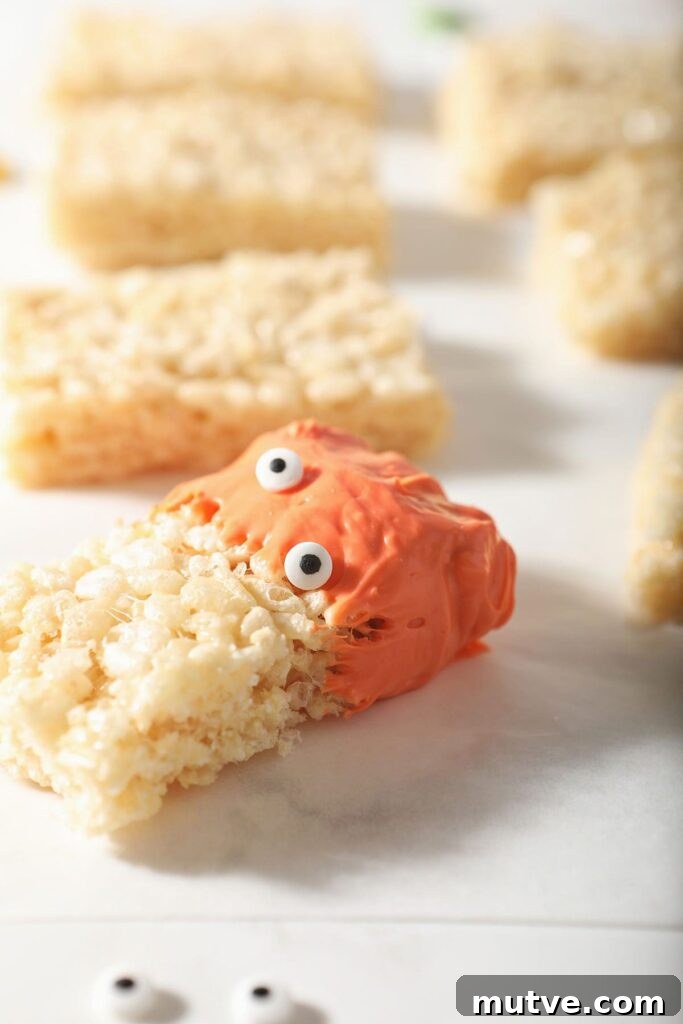 A rice krispie treat dipped in orange candy with candy eyeballs