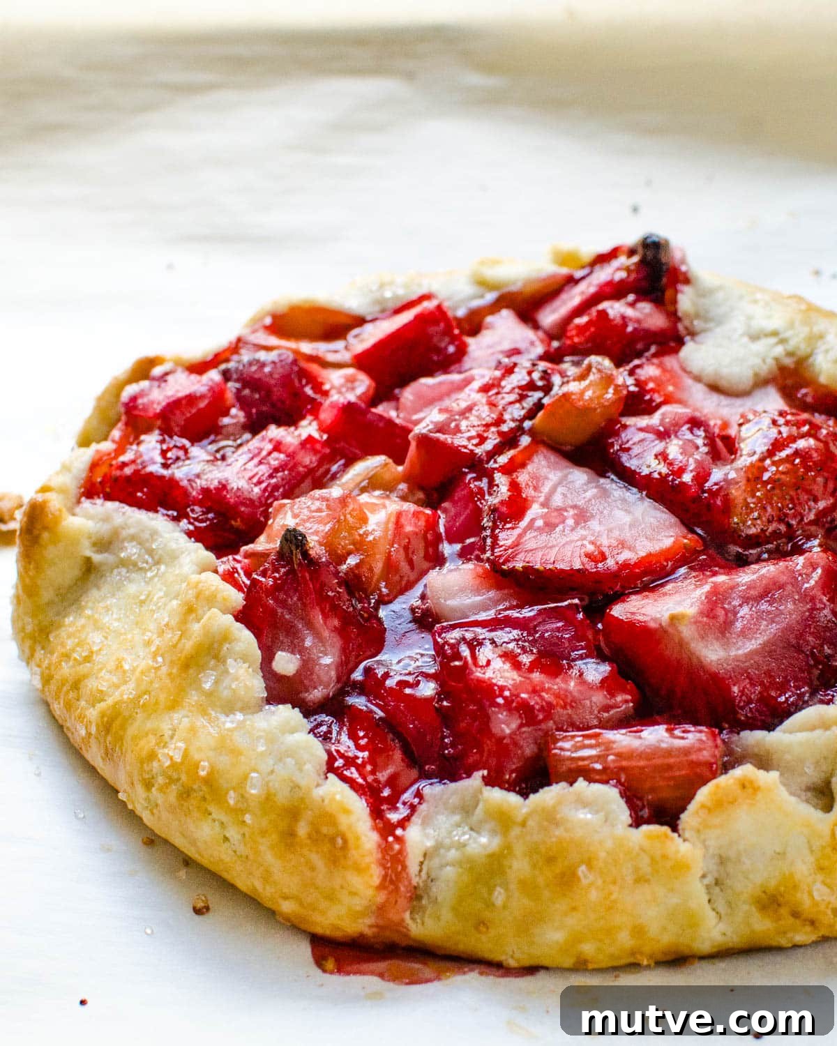 Rustic Strawberry Rhubarb Galette with Flaky Crust 13 A baked strawberry rhubarb galette on parchment.