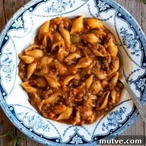 Pasta and lentils in a blue and white vintage bowl sitting on a wooden surface.