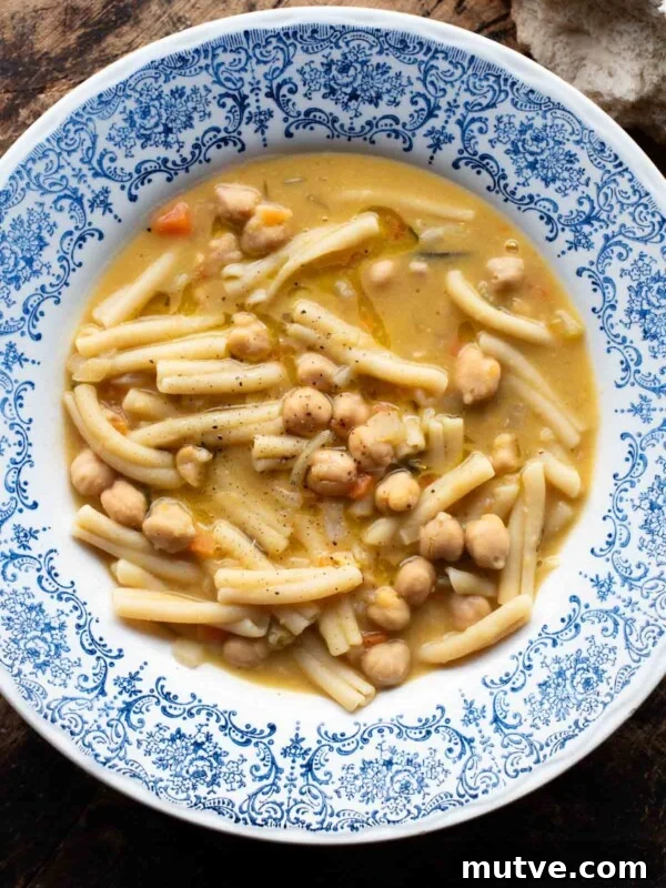 An overhead shot of pasta e ceci (psta and chickpeas) in a blue bowl on a wooden surface.