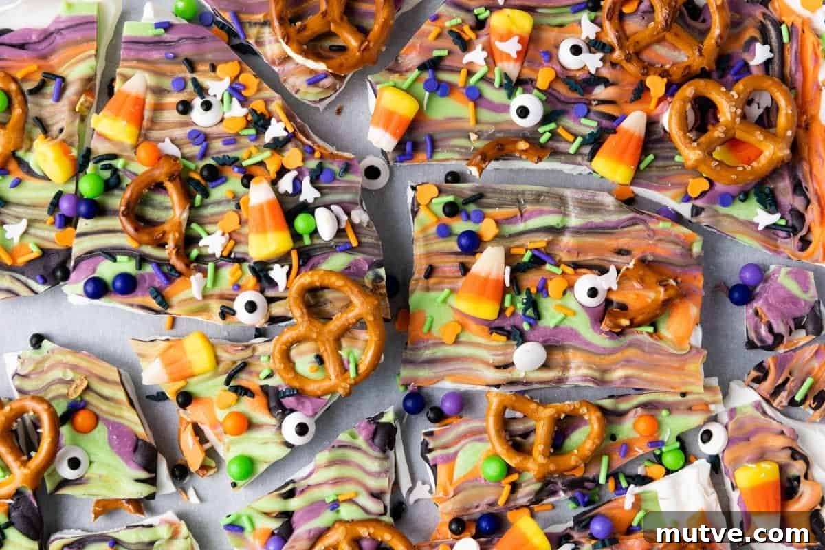 29 Halloween Treats That Beat Your Trick-or-Treat Candy 14 Halloween-themed chocolate bark topped with pretzels, candy corn, candy eyeballs, and colorful sprinkles, broken into irregular pieces.