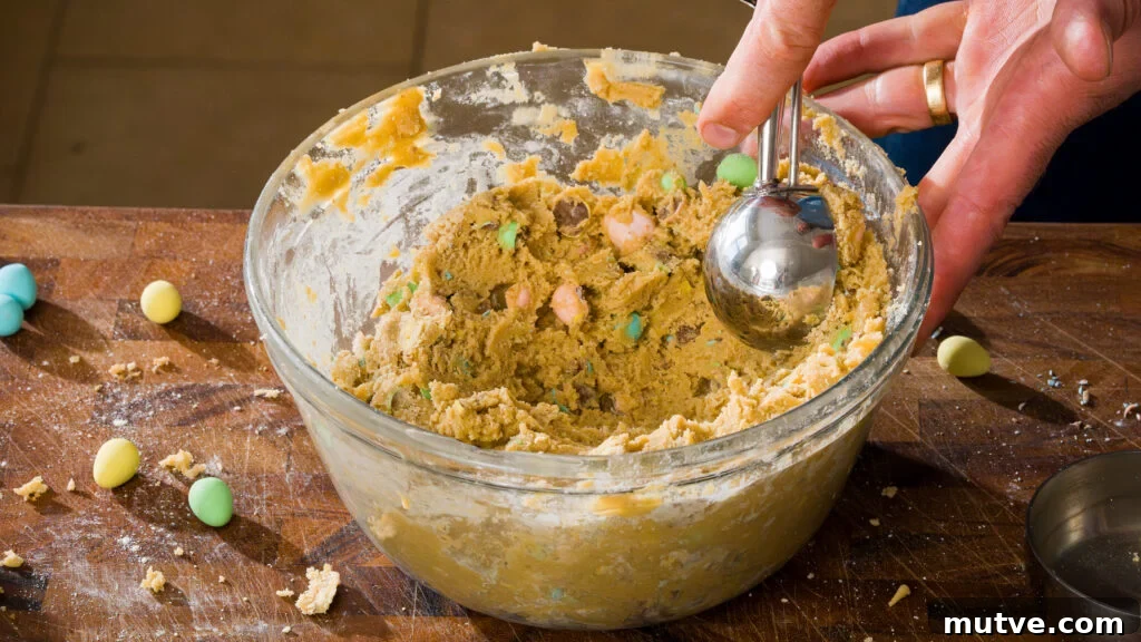 Mini egg cookie batter in a bowl with a scoop being taken out.