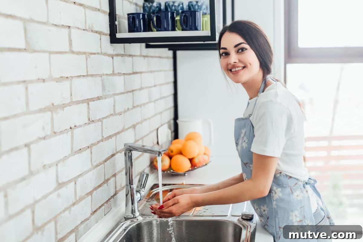 woman in apron washing hands kitchen sink