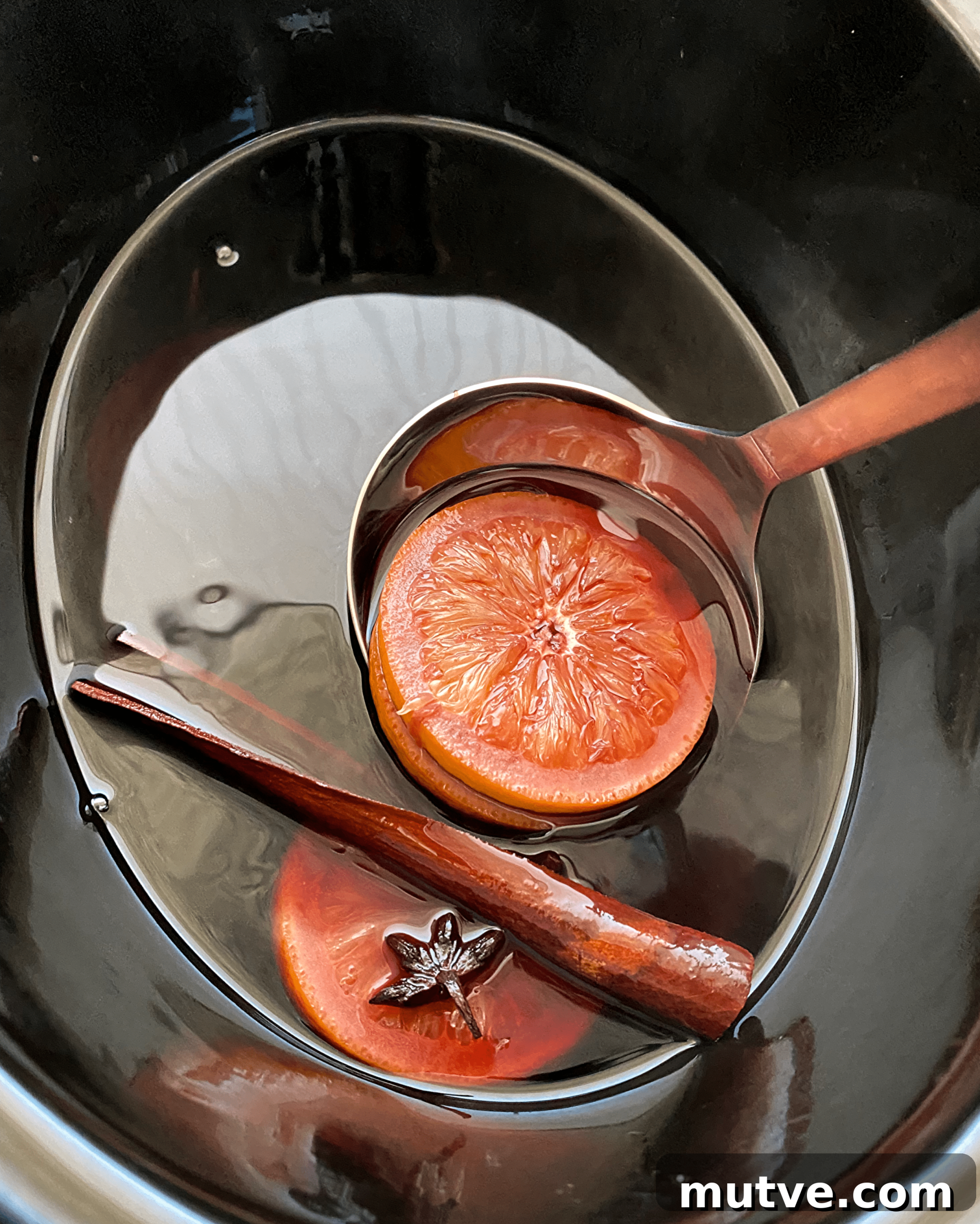 Slow Cooker Mulled Wine Recipe: Crockpot Spiced Wine 5 overhead shot of cooked mulled wine in a black slow cooker