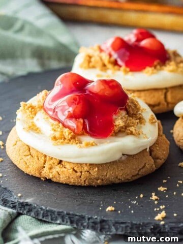 Baked cherry cheesecake cookie on black plate.