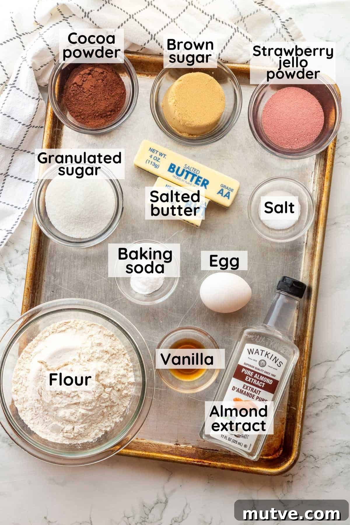 Labeled ingredients for neapolitan cookies in glass bowls on metal baking sheet.