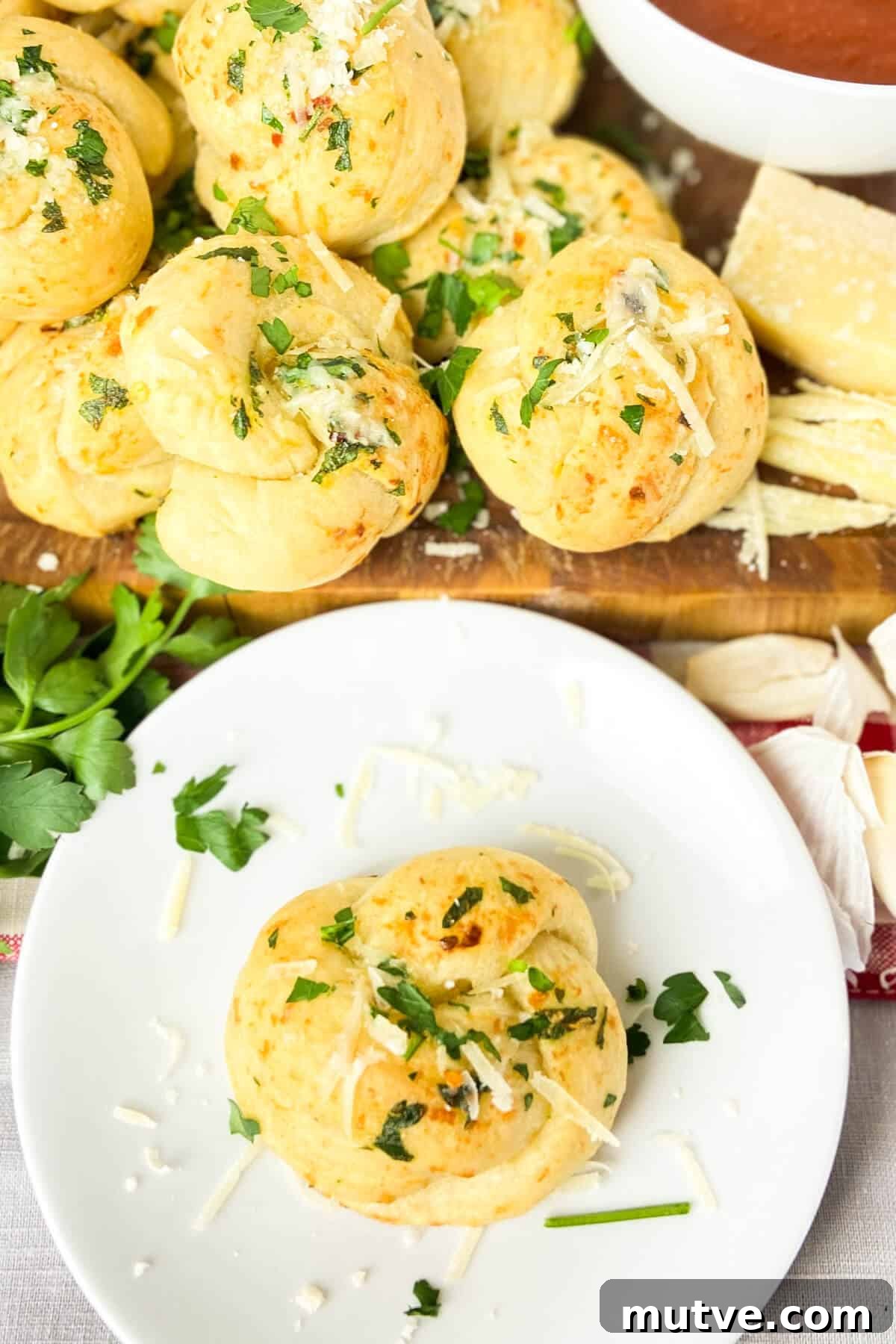 Homemade Garlic Knots Recipe with Herb Butter 15 Serving, with a bowl of marinara sauce.