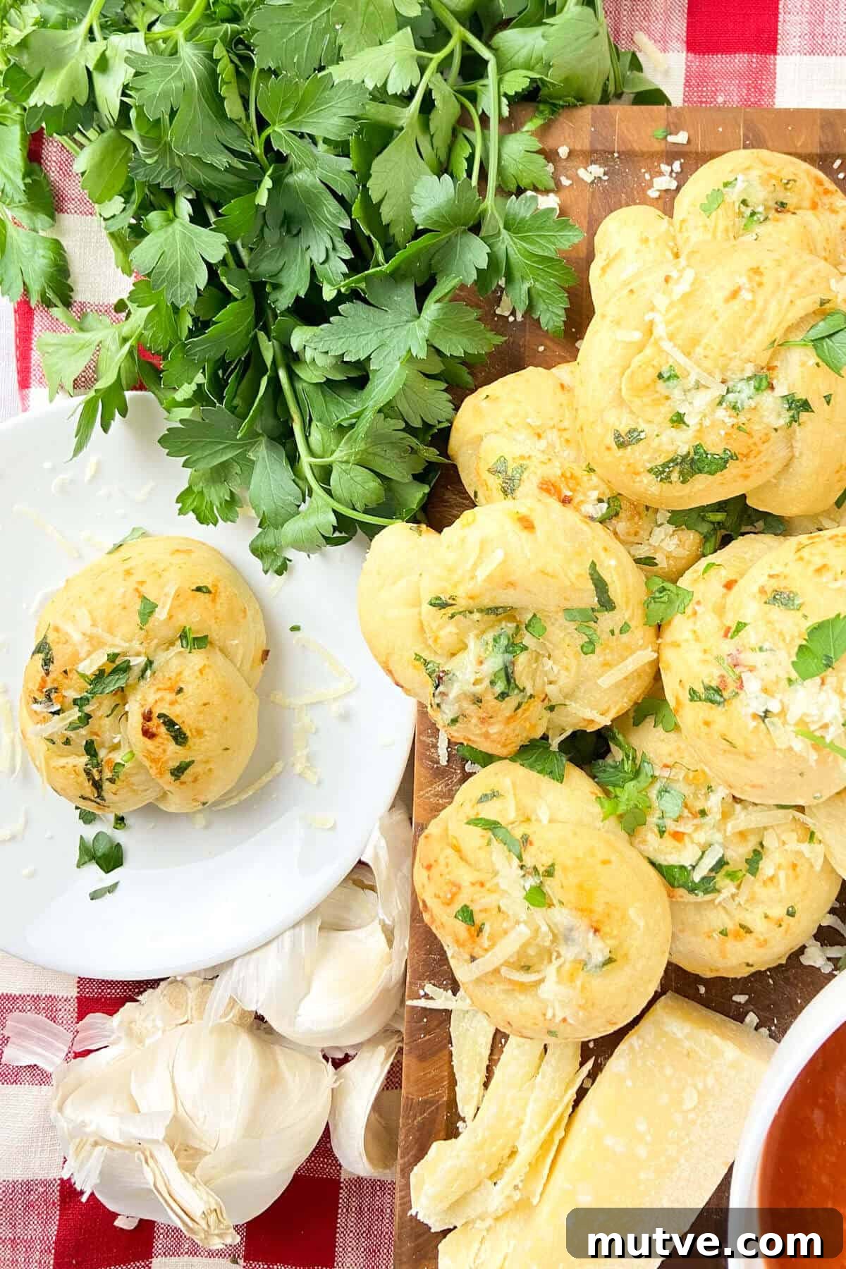 Homemade Garlic Knots Recipe with Herb Butter 4 Served on plate, with red gingham checked napkin.