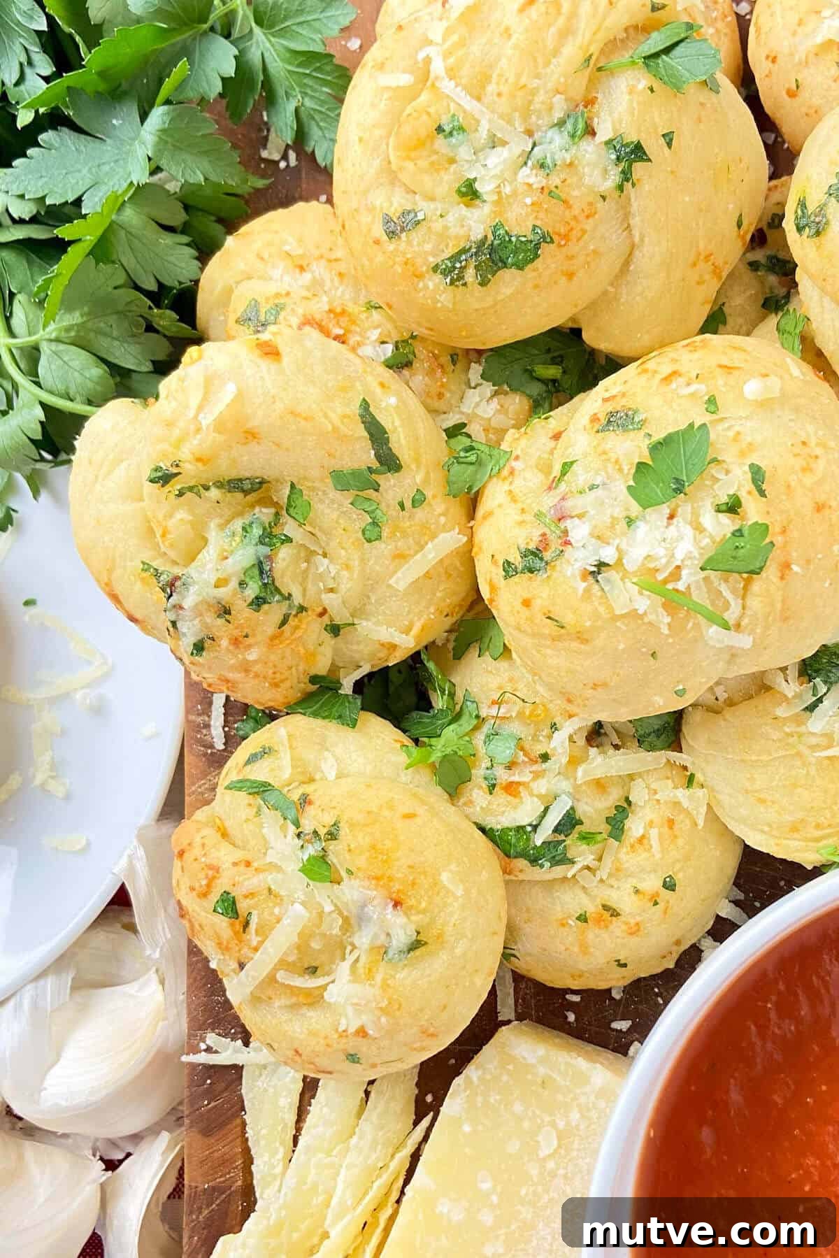 Homemade Garlic Knots Recipe with Herb Butter 8 Finished knots, sprinkled with extra cheese and parsley.