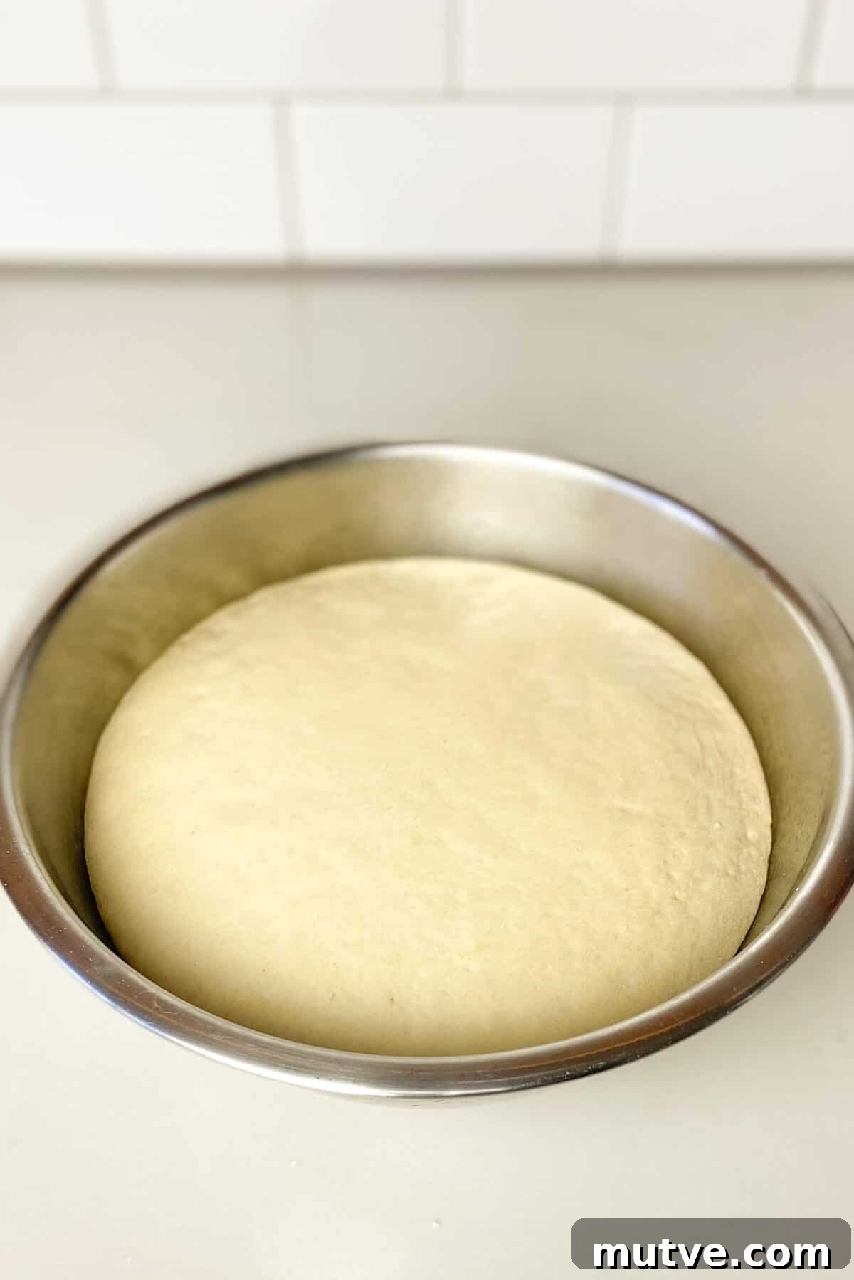 Homemade Garlic Knots Recipe with Herb Butter 10 Dough in stainless steel bowl has doubled in size.