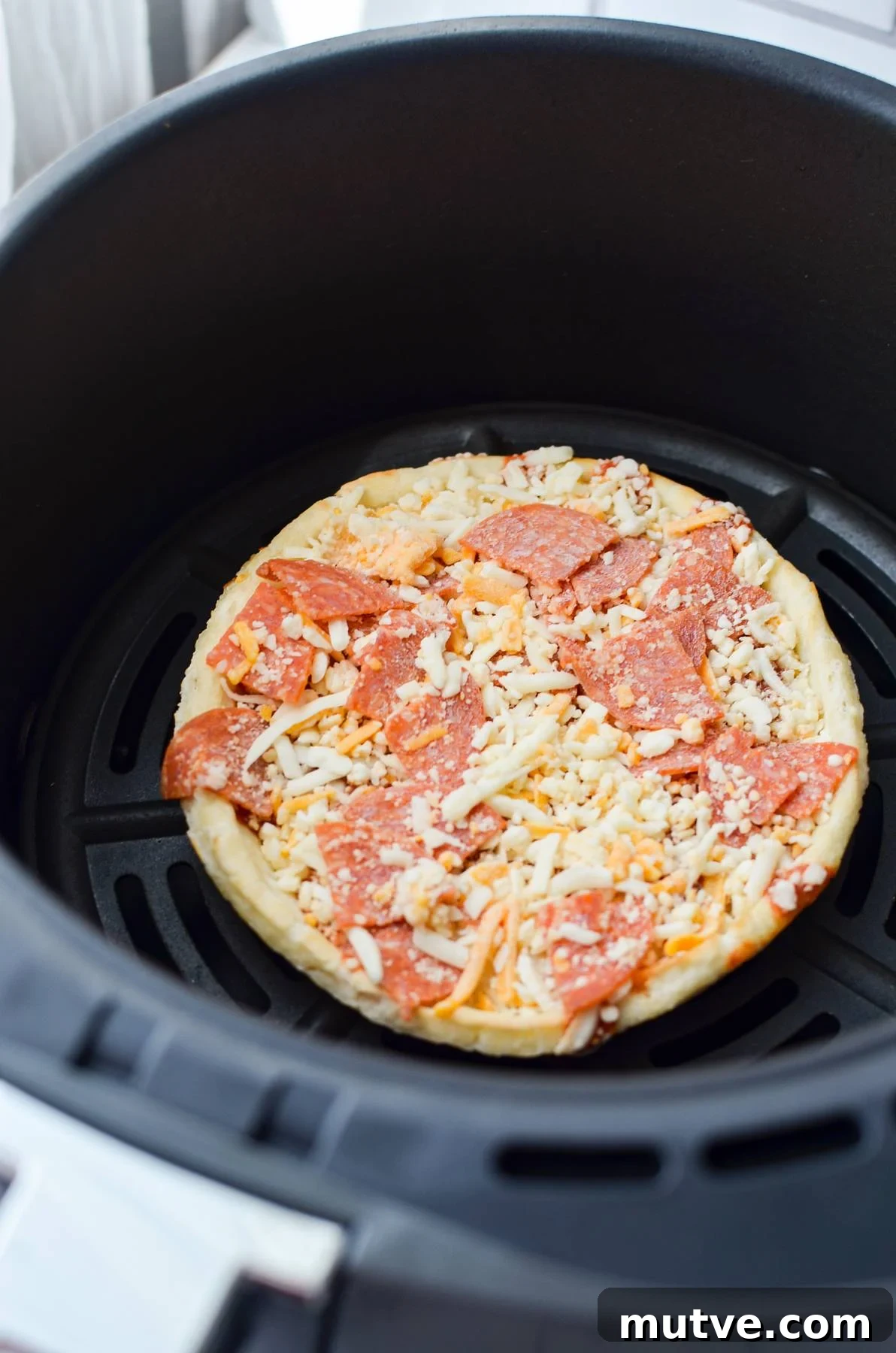 Crispy Frozen Mini Pizzas in the Air Fryer 4 A frozen pizza in an air fryer basket.
