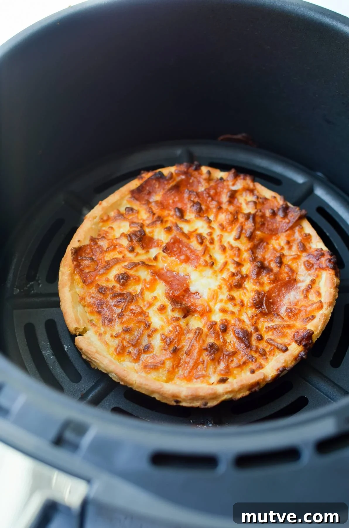 Crispy Frozen Mini Pizzas in the Air Fryer 5 A mini pizza cooked in an air fryer basket.