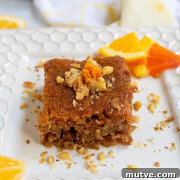 Tishpishti Honey Almond Cake with Citrus Syrup 21 Honey orange cake on a white plate with slices of citrus in the background.