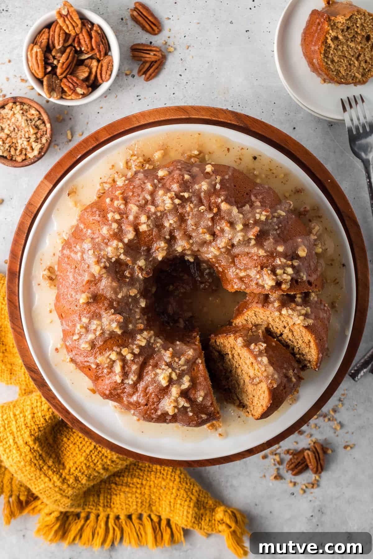 Spiced Sweet Potato Bundt Cake with Maple Glaze 3 A top down shot of a partially sliced bundt cake with pecan icing.