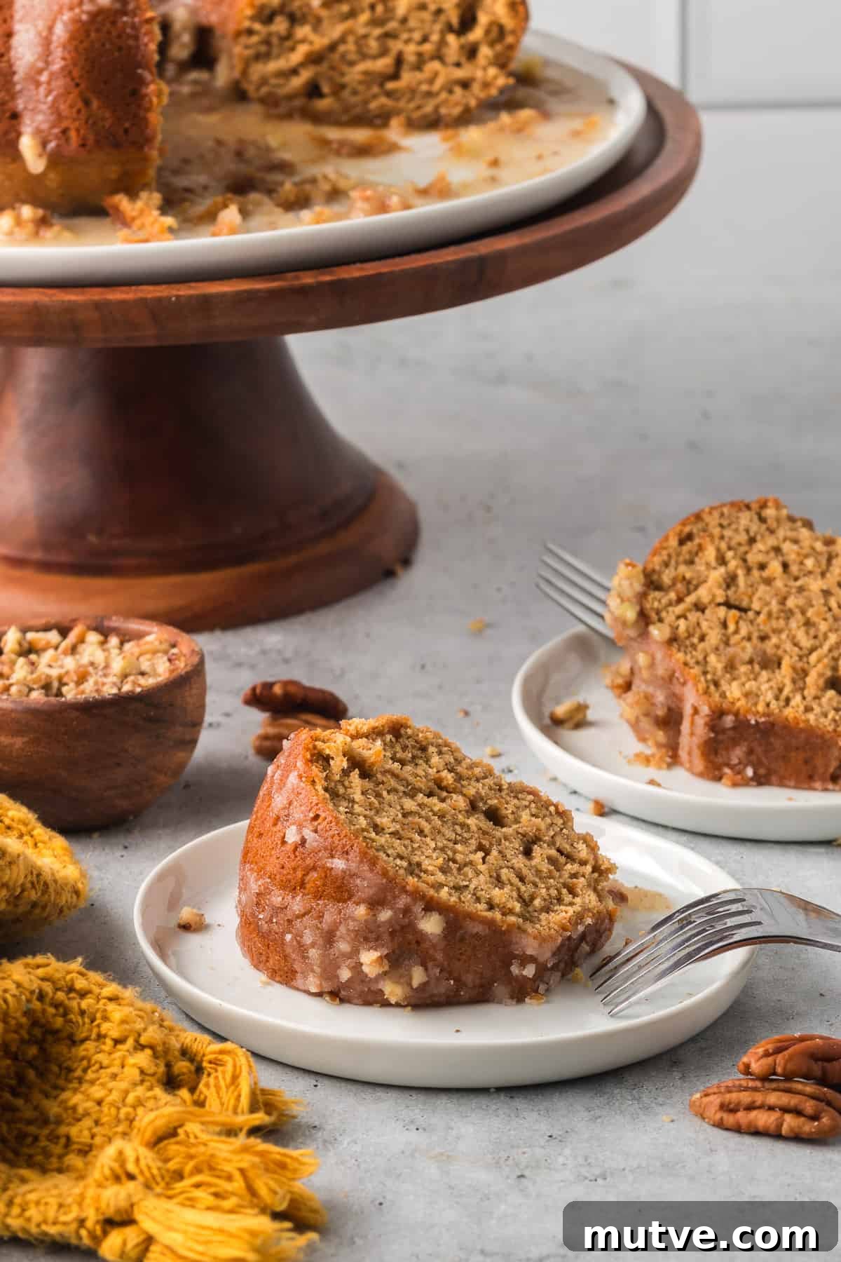 Spiced Sweet Potato Bundt Cake with Maple Glaze 10 Two slices of sweet potato bundt cake next to a wooden cake pedestal.
