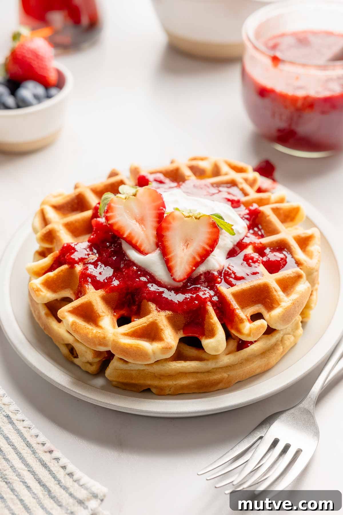 Fluffy Gluten-Free Belgian Waffles Recipe 4 Two Belgian waffles topped with strawberry sauce, whipped cream and strawberry cut in half.