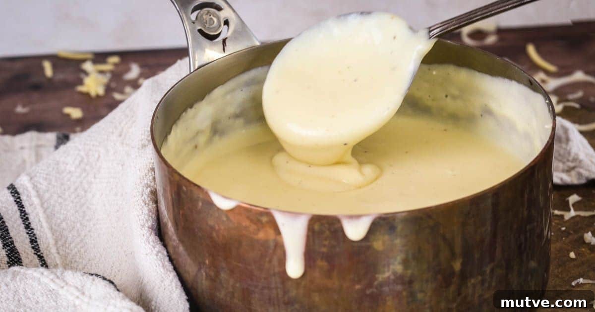 Spooning gluten-free cheese sauce from saucepan showing velvety creamy texture.