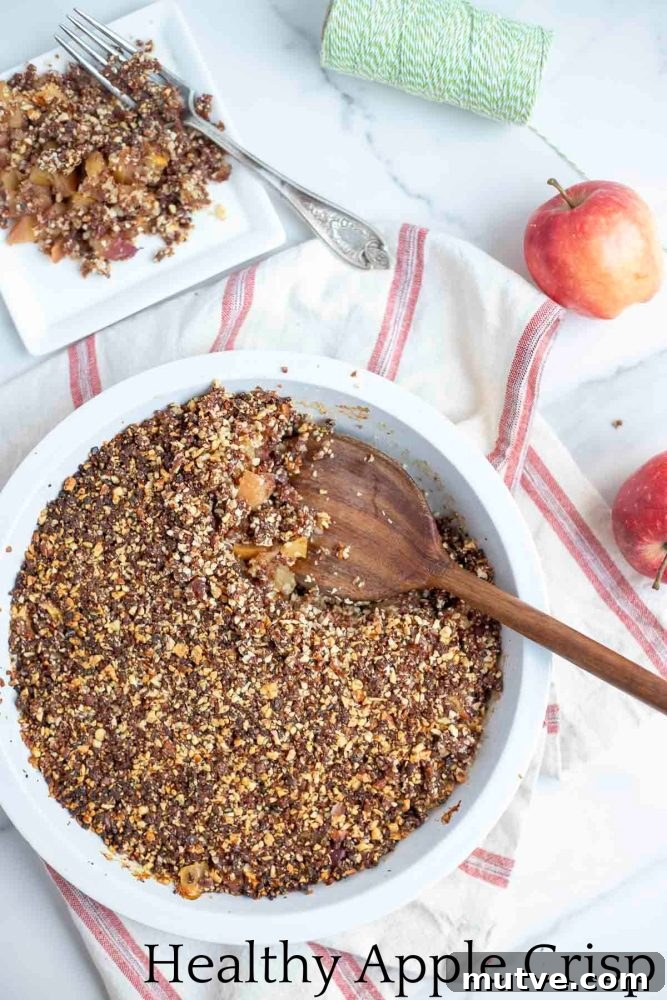 Gluten-Free Apple Crisp Recipe with Oat Crumble 2 overhead photo of a healthy apple crisp in a pie plate with a wooden spoon in the dish. The pie dish is on a white and red stripped towel with a plate of crisp and apples in the background