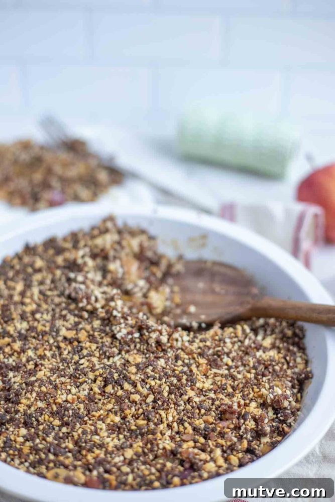 Gluten-Free Apple Crisp Recipe with Oat Crumble 5 apple crisp in a pie plate with a wooden spoon taking a scoopful out
