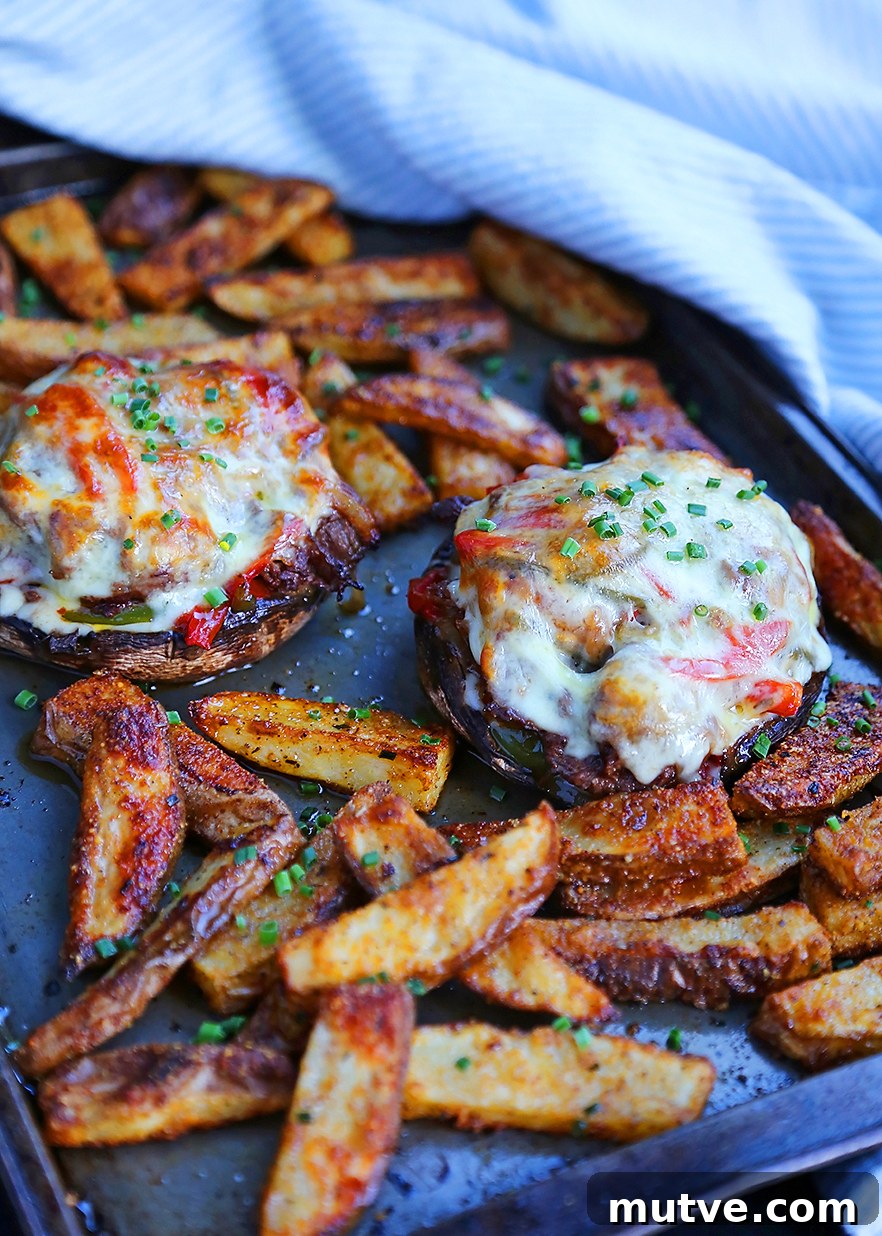 Philly Cheesesteak Stuffed Portobello Mushrooms Recipe 2 Philly cheesesteak stuffed portobello mushrooms on a baking sheet
