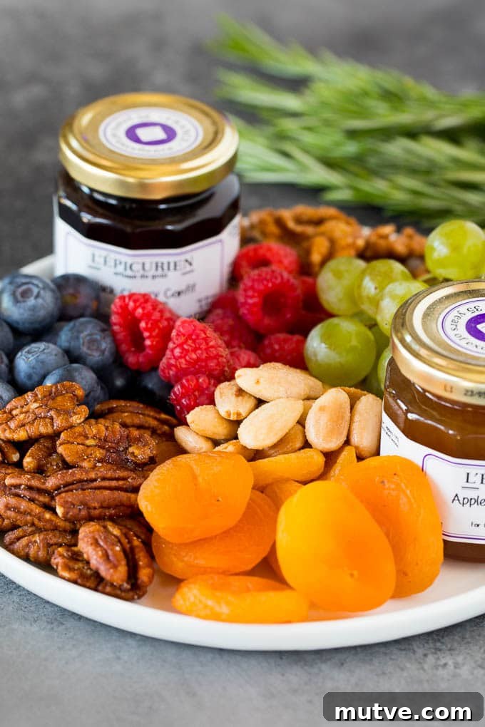 A plate with fresh and dried fruit, nuts and jam.