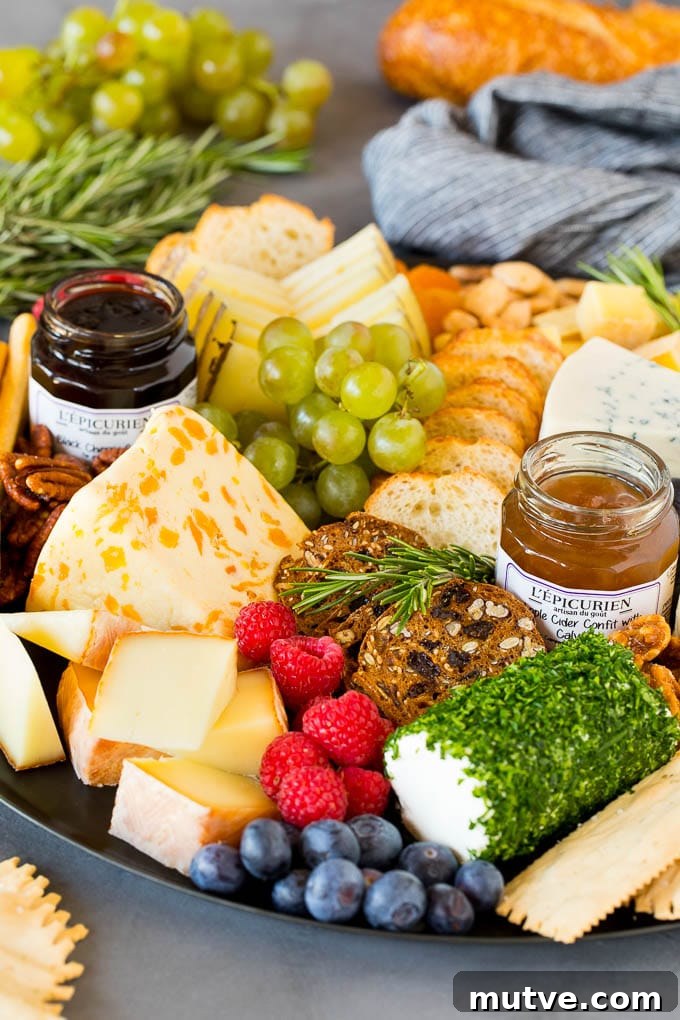 A cheese board with crackers, fruit, nuts and jam.