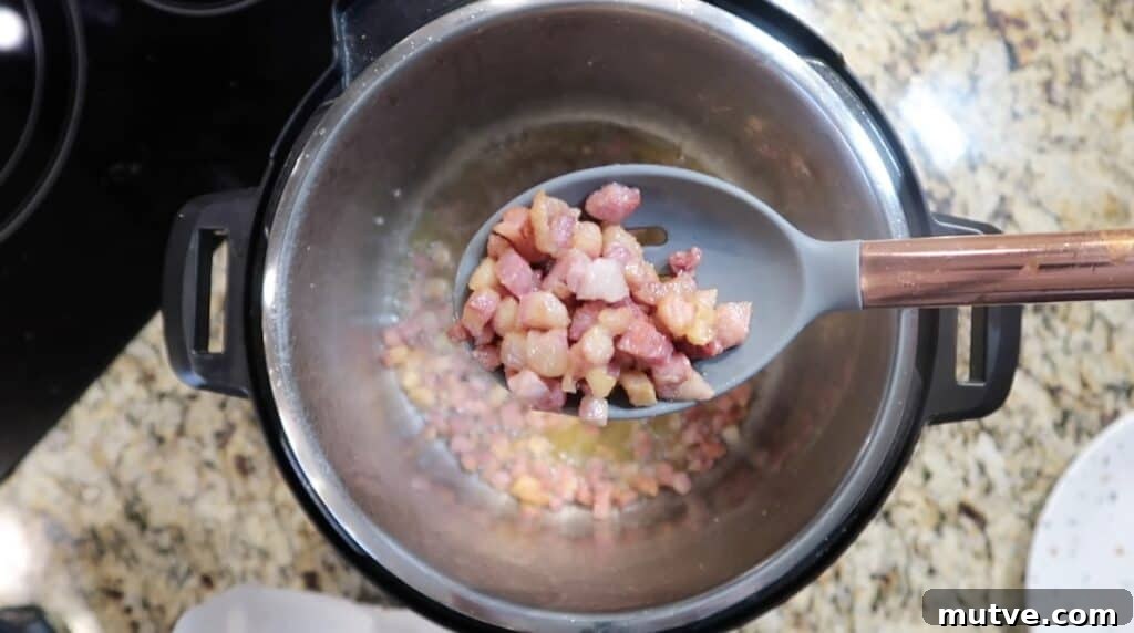 Creamy Instant Pot Chicken Baconara Pasta 9 Removing pancetta from pot with a slotted spoon.