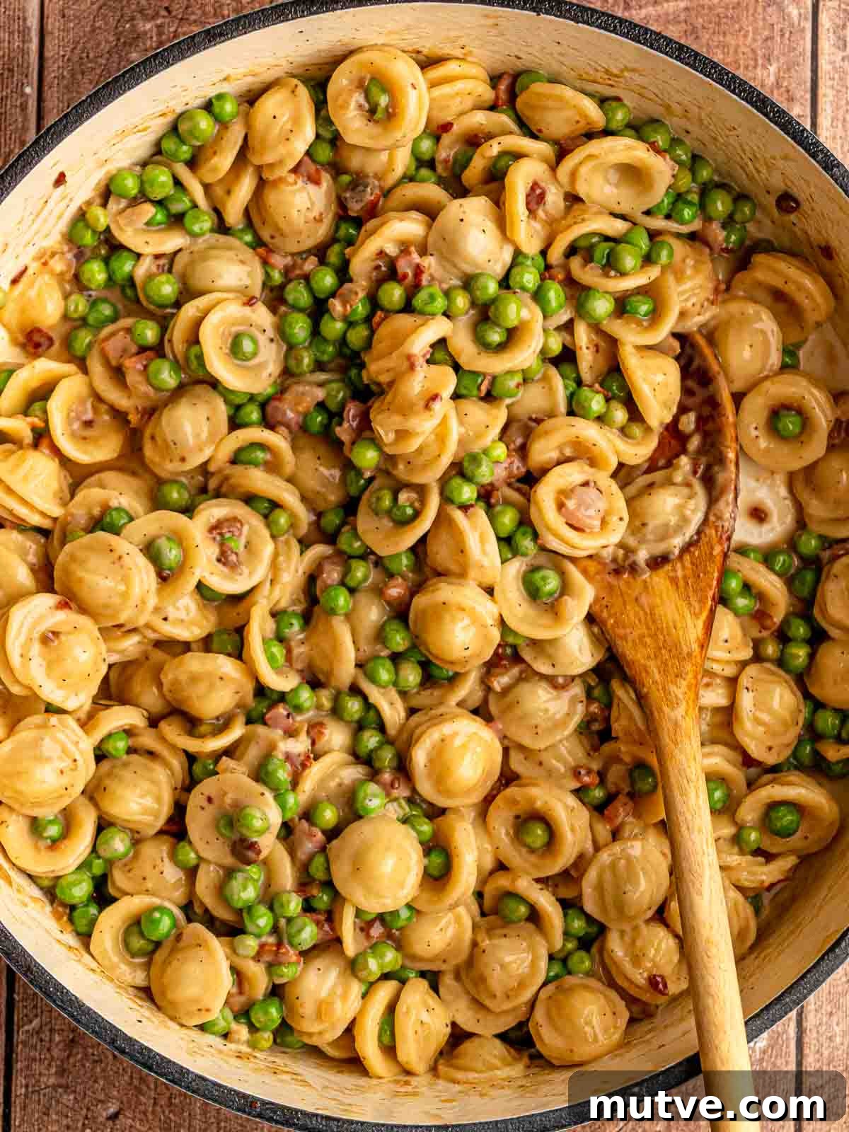 Wooden spoon in a pan of pasta.