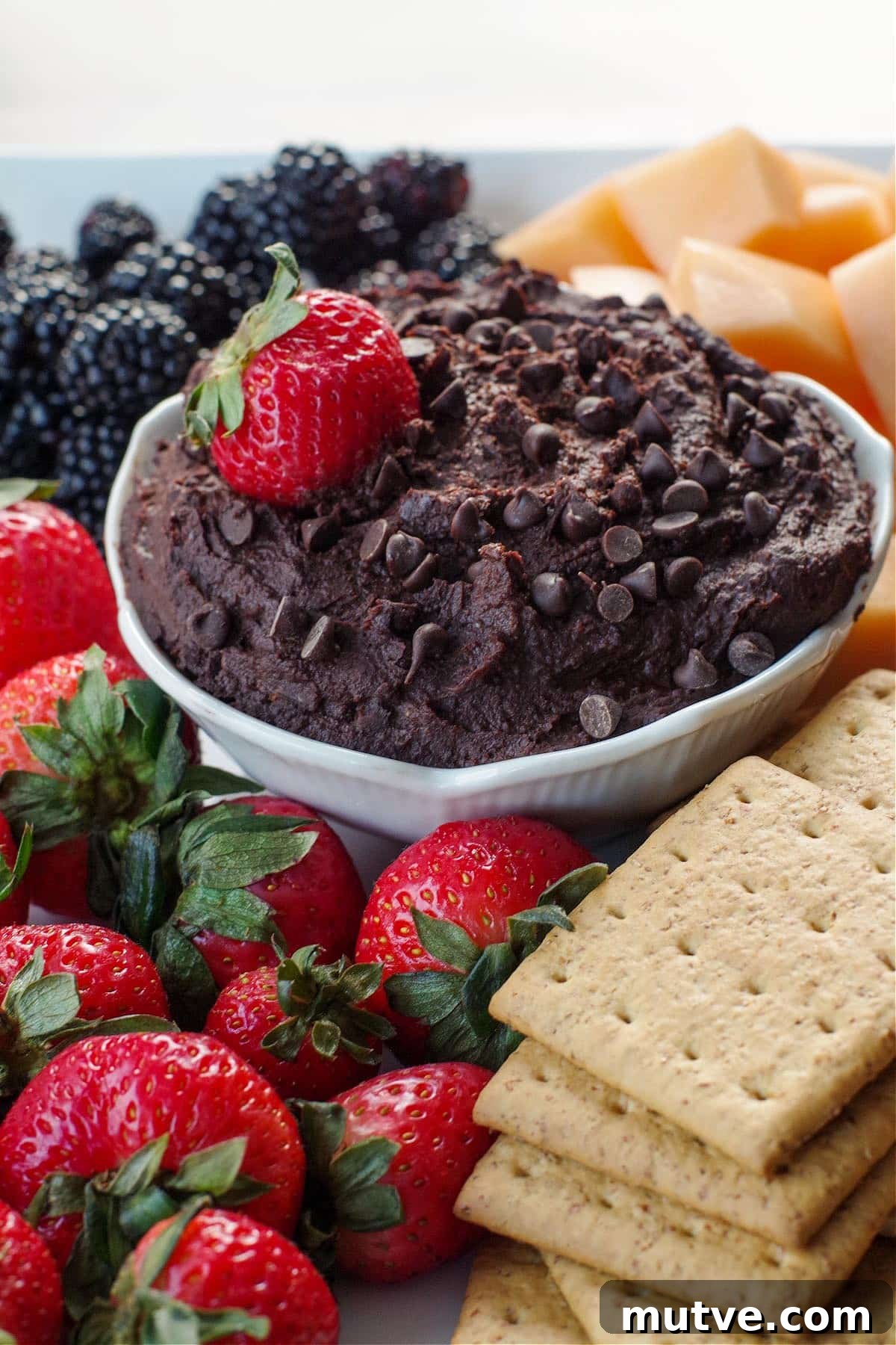 Chicken Tortilla Pinwheels Recipe: Cheesy Party Appetizer 14 Dark Chocolate Hummus in a white petal bowl, with a strawberry in the hummus, on a platter of fruit and graham crackers