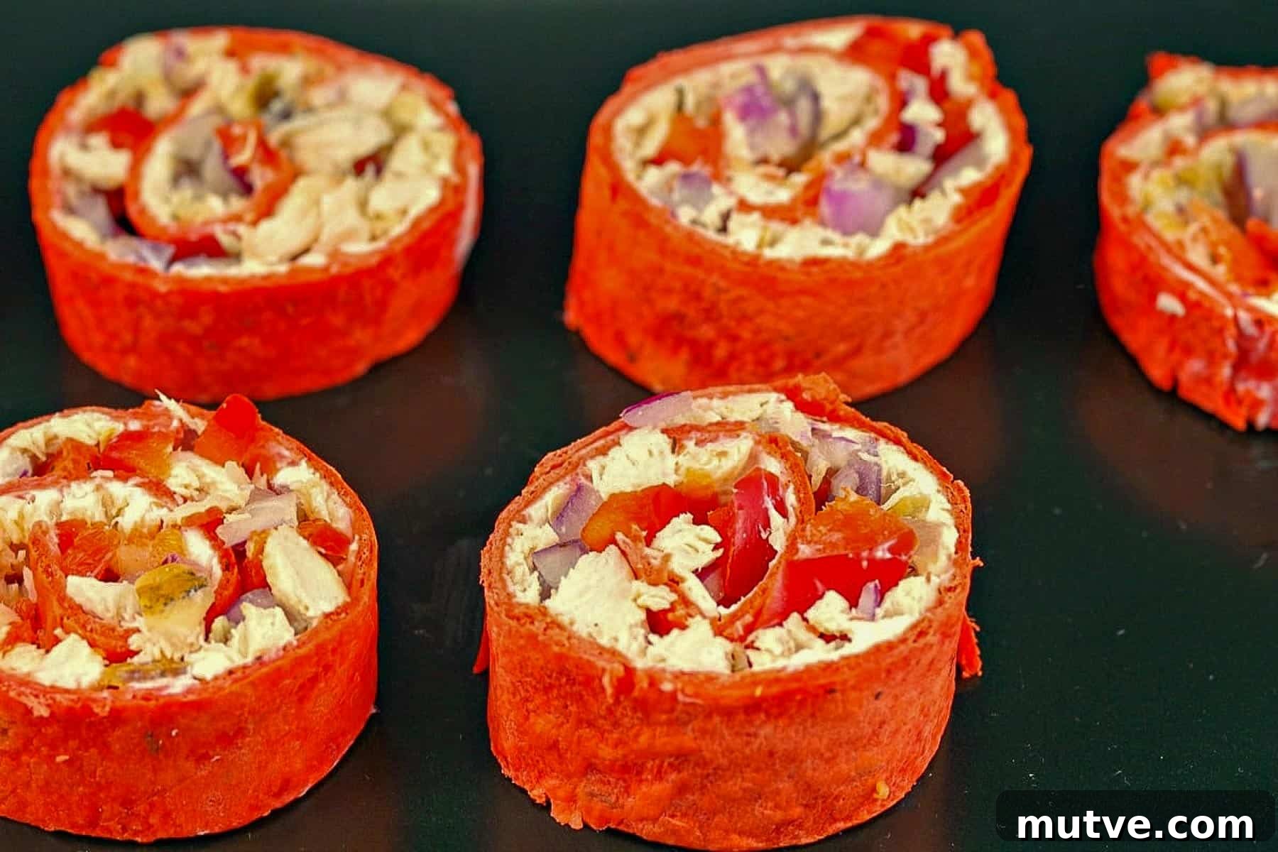 Chicken Tortilla Pinwheels Recipe: Cheesy Party Appetizer 3 Chicken Tortilla Pinwheels on a black tray