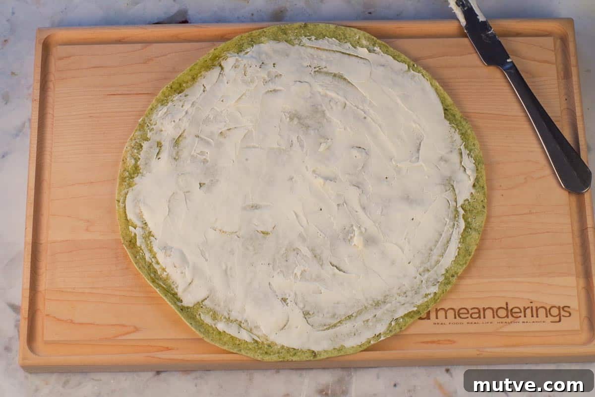 Chicken Tortilla Pinwheels Recipe: Cheesy Party Appetizer 7 cream cheese spread onto tortilla on cutting board.
