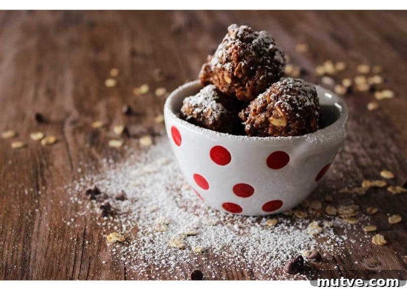 White bowl sitting on a brown table with No-Bake Quinoa Protein bites, oats and powdered sugar on table.