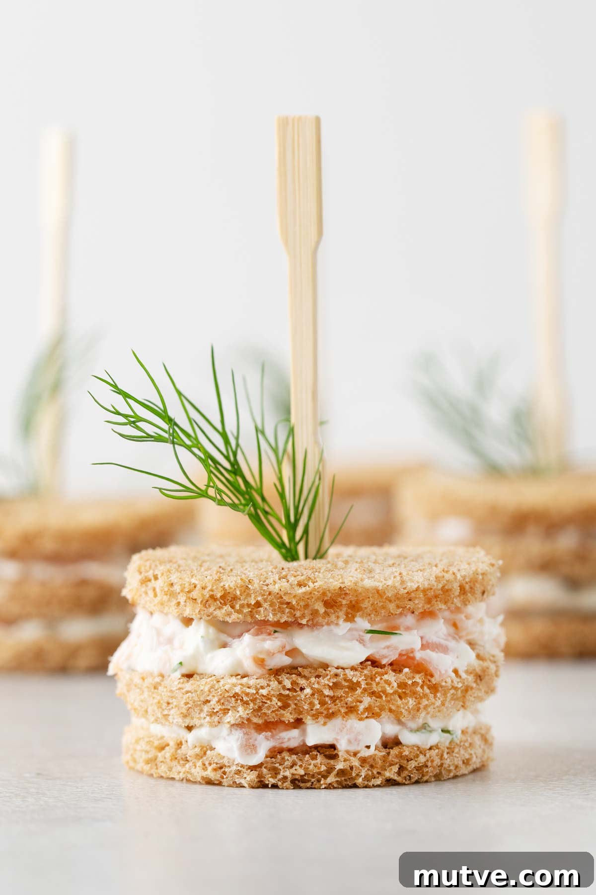 Smoked Salmon Tea Sandwiches Recipe with Cream Cheese and Dill 11 Close up of Smoked Salmon Tea Sandwiches held together by cocktail fork.