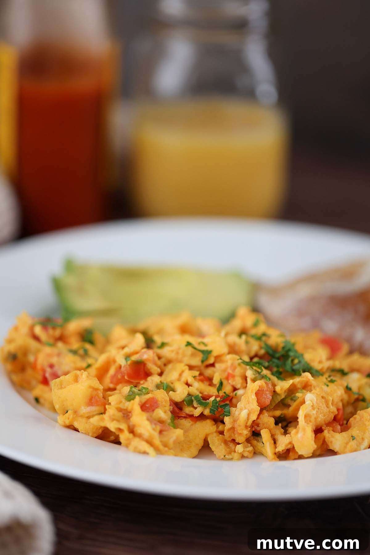 huevos pericos with hot sauce and orange juice on the side.