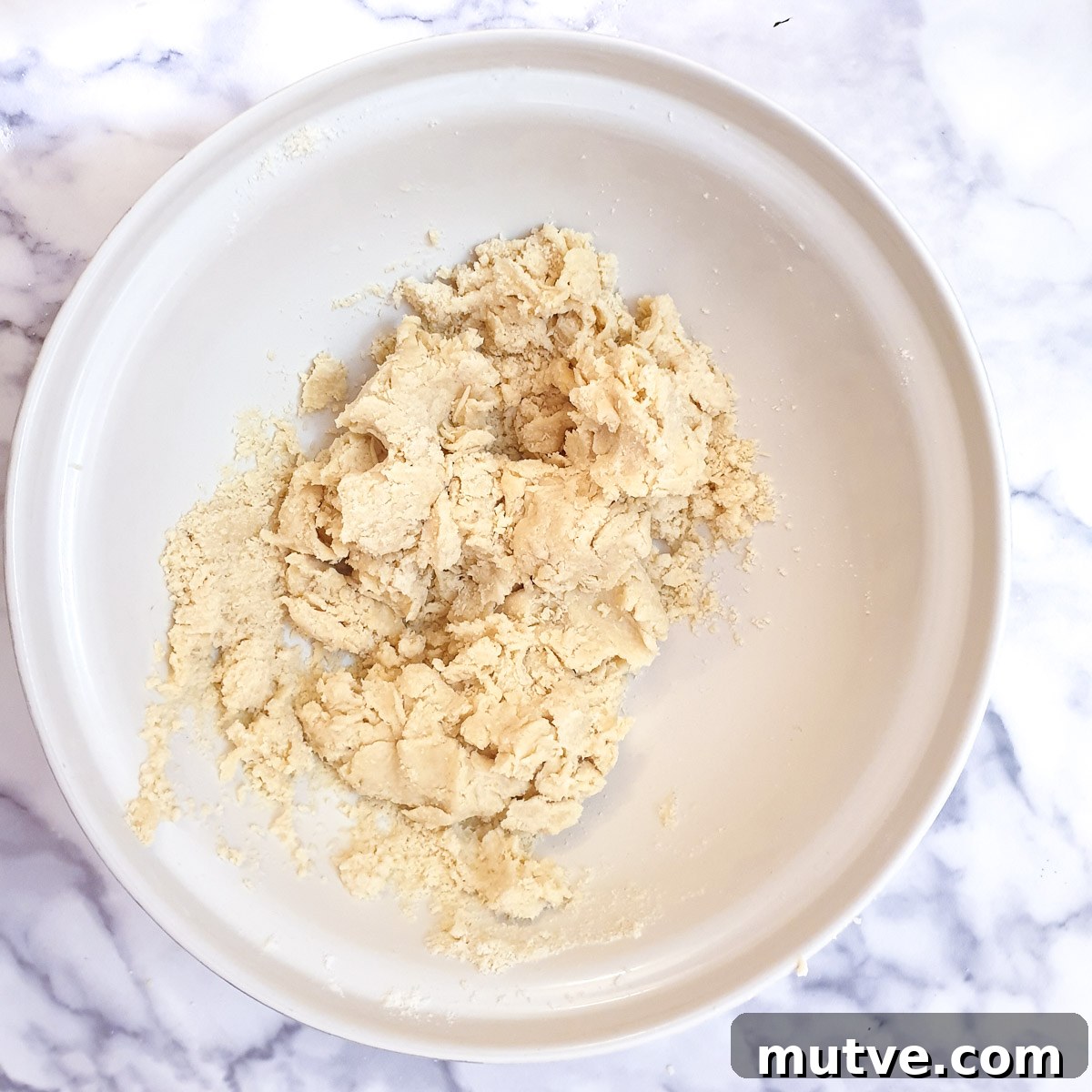 A ball of shaggy dough in a mixing bowl.