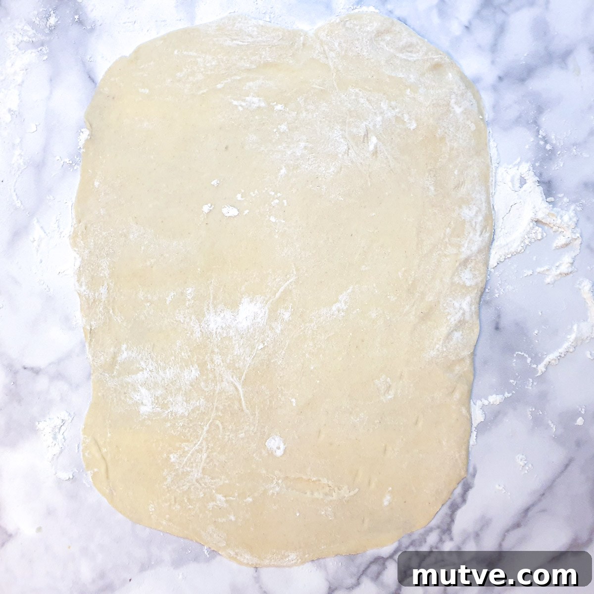 A rectangle of rolled pastry on a table.