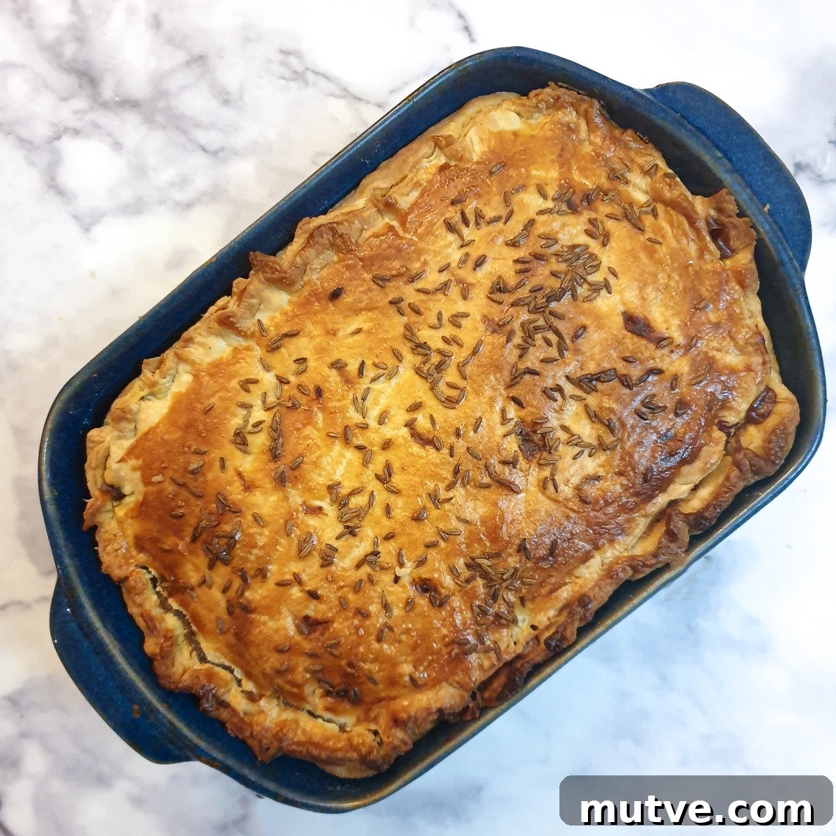Overhead shot of a baked Moroccan lamb pie in a blue dish.
