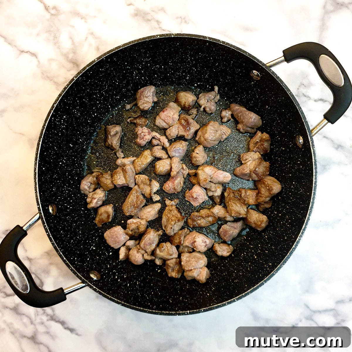 Lamb cubes browning in a frying pan.