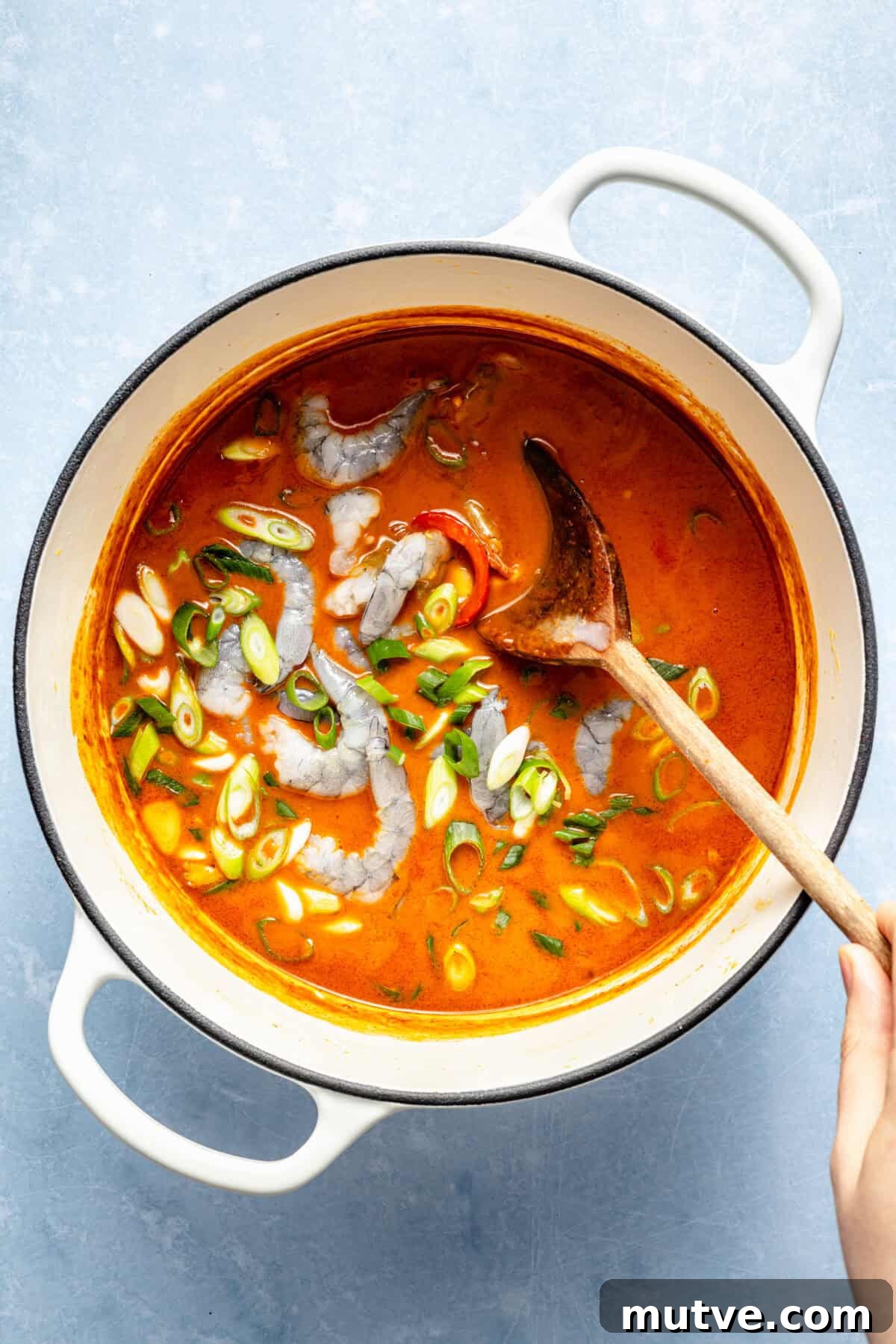 a large pot of gochujang soup with shrimp and green onions