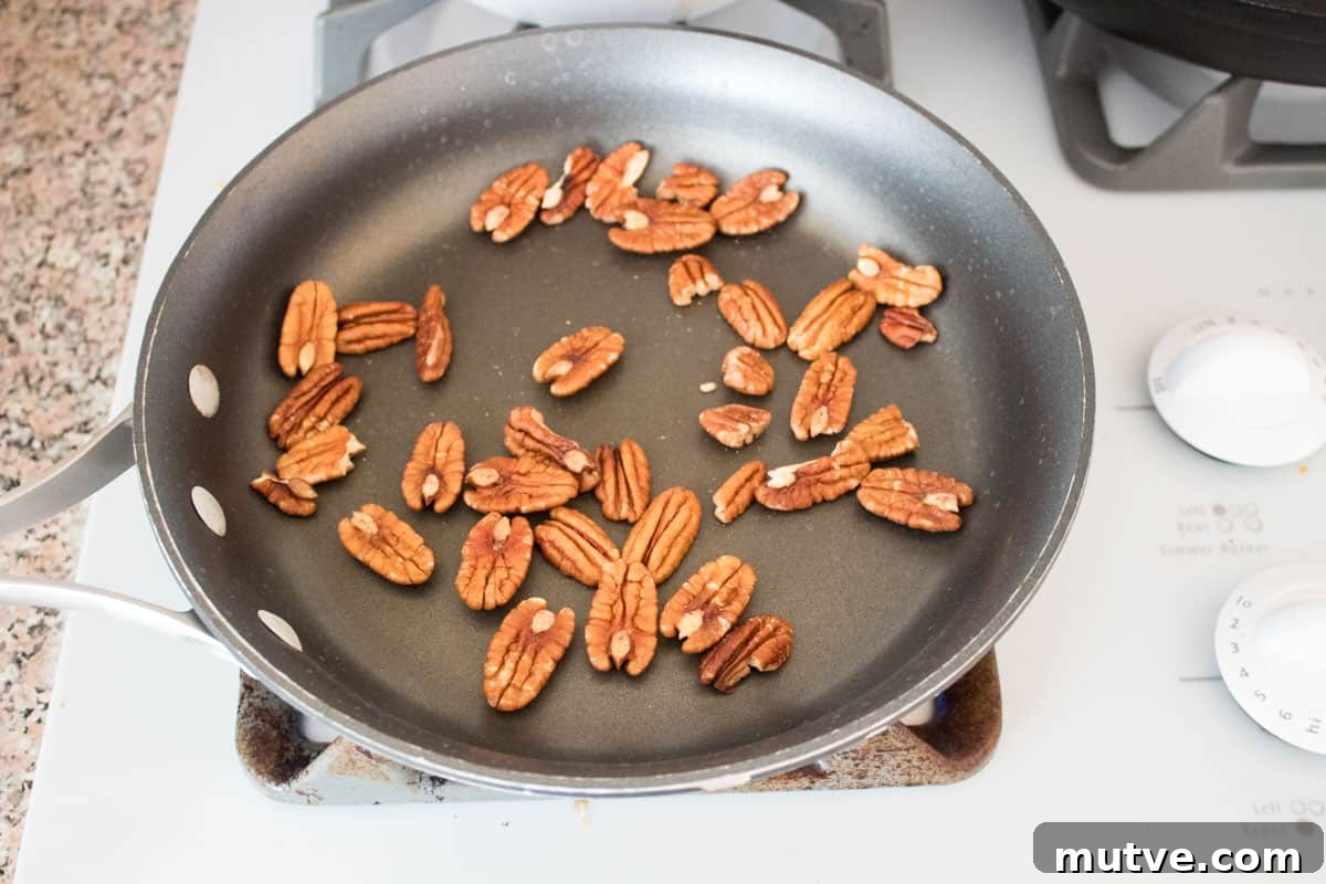 Pecan halves in a skillet on a stove.