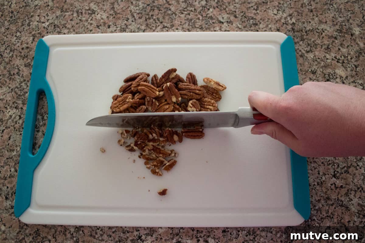 Pecans being chopped on a cutting board.