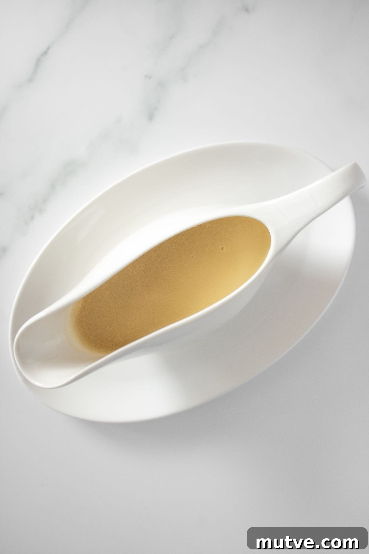 3-Ingredient Chicken Gravy Without Pan Drippings 2 White jug on white plate of Chicken Gravy.